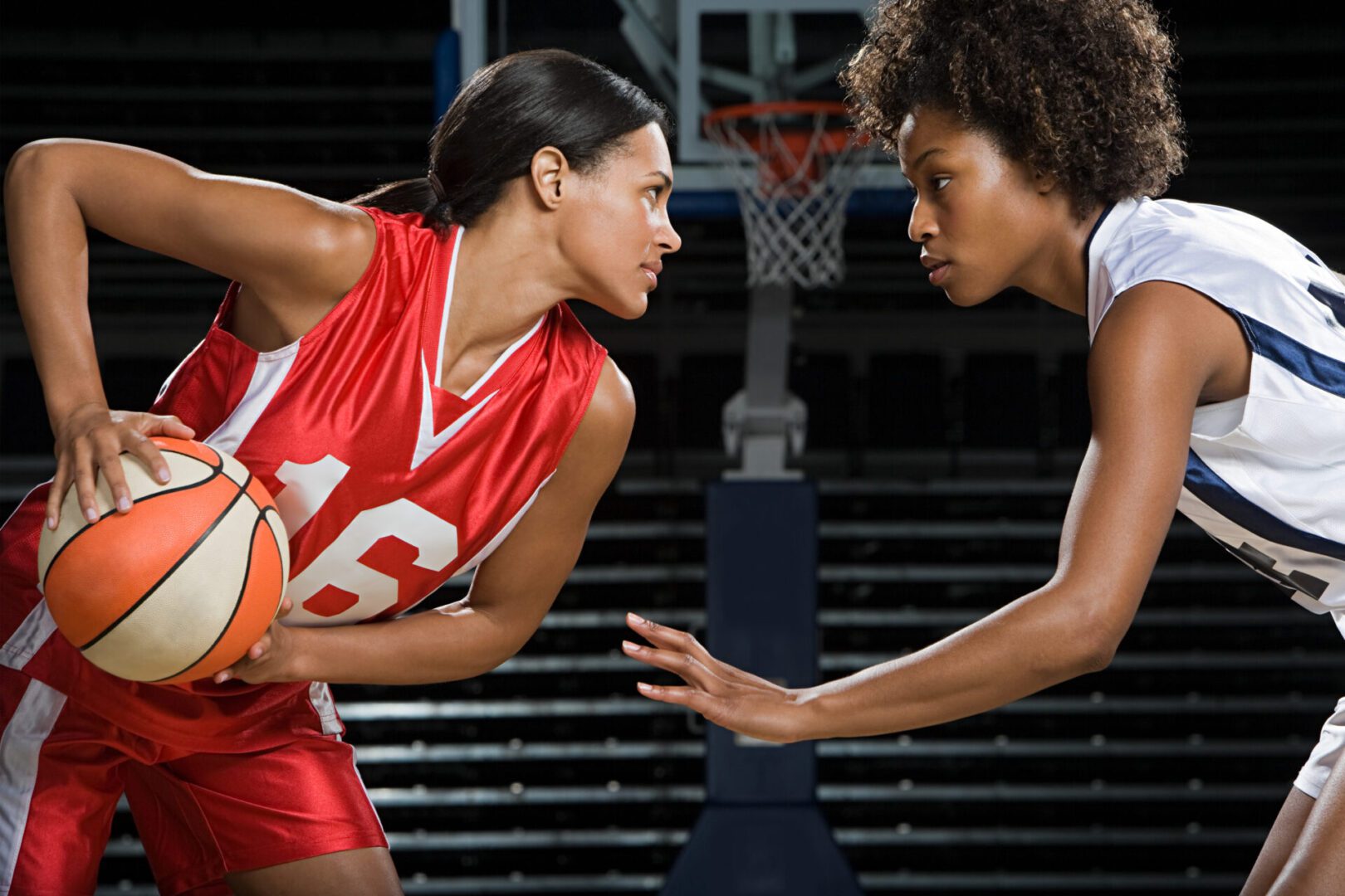 Two women playing basketball in a game.